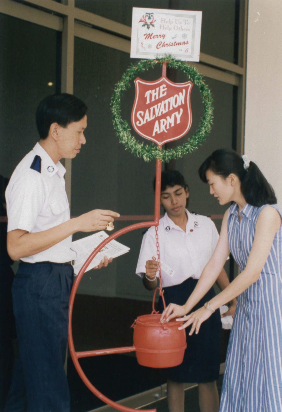 A desire to meet the needs of the poor has seen Vijaya Muniandy (centre) manning the Salvation Army's Christmas Kettle stands for the last 23 years. Photo courtesy of the Salvation Army Singapore.