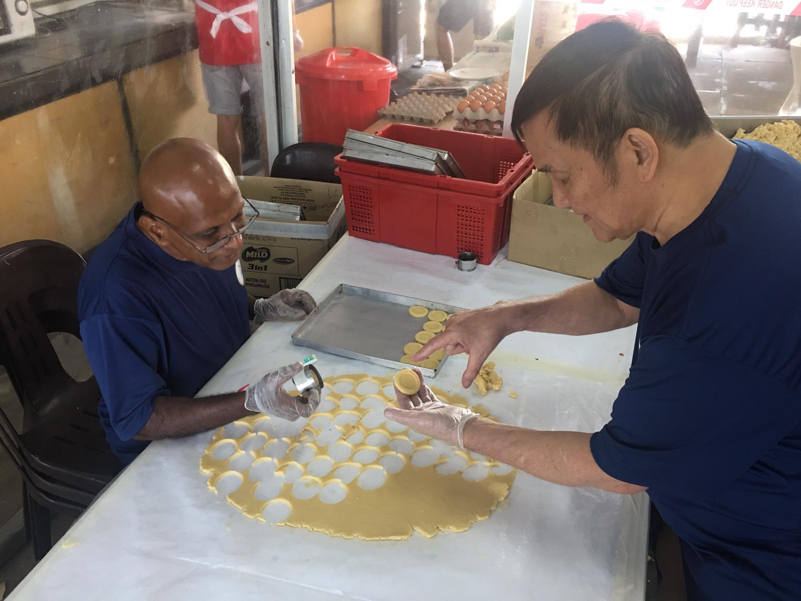 Pastor Philip Chan (right) showing a resident what to look out for when cutting the pastry. Photo courtesy of Sart S.