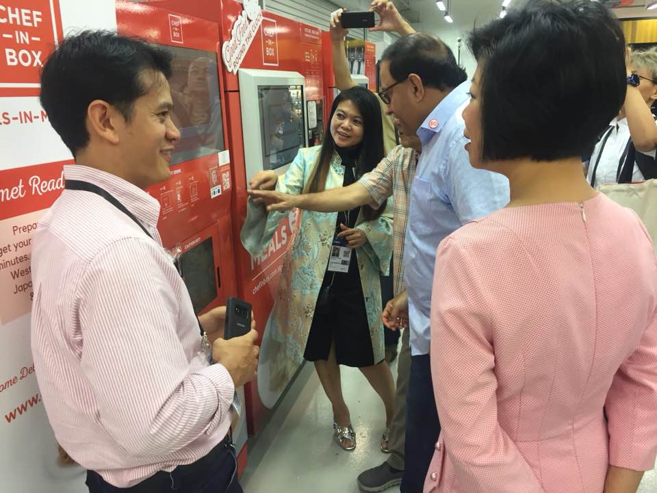 Senior Minister of State for Communications and Information, Sim Ann (right) and Communications and Information Minister S Iswaran (second from right) invited JR Group to set up their vending machines, Chef-in-Box at the media centre set up for the Trump-Kim summit held in Singapore in June 2018.