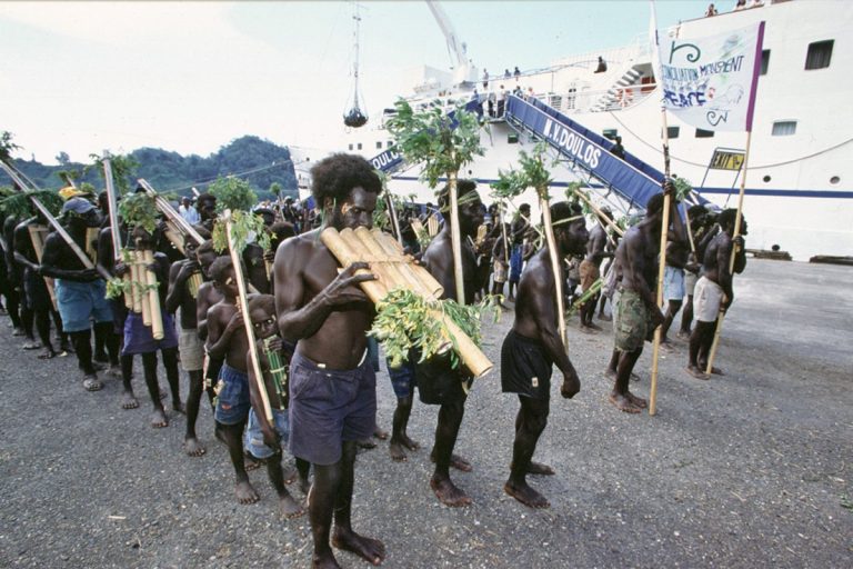 Doulos' leaders among local people playing traditional instruments as they mark the reconciliation ceremony in Bougainville with a procession on the quayside (By Tom Brouwer, OM)