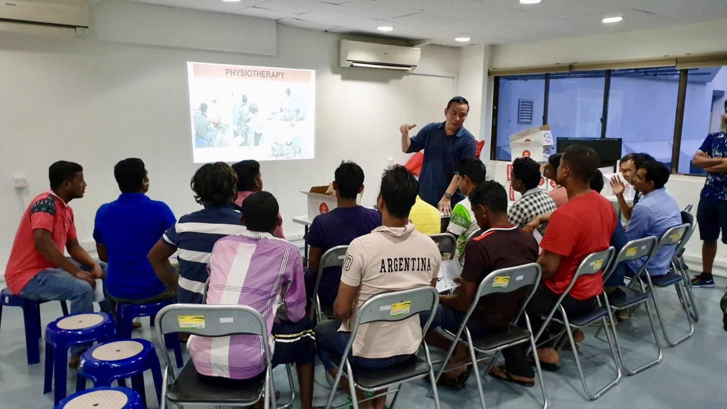 A volunteer sharing with the migrant workers the services they can enjoy at SG Care Welcome Centre.