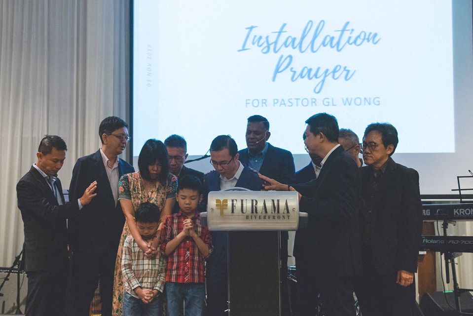 Ps Guna and other church leaders praying for Ps Guoliang and his family during his installation as senior pastor, which was held during Agape Baptist Church's 35th anniversary celebrations.