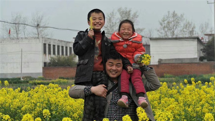 Huang with his two older children at their family field in China.