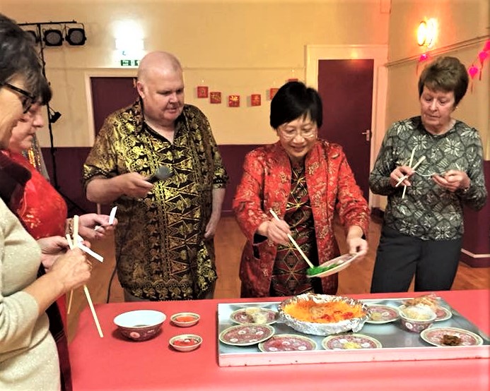 The 'Chopsticks Vicar' introducing her friends to the traditional practice of 'Lo Hei' at a 2018 New Year Party in Gainford. 