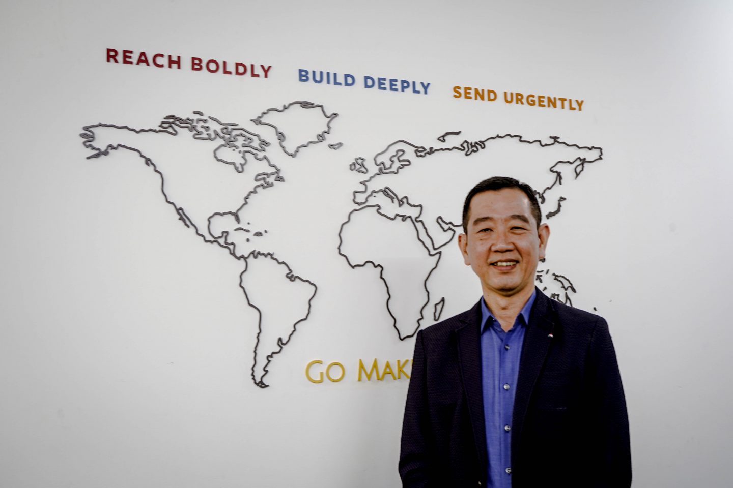 Kok Hiang in front of the global map in Cru's office. 