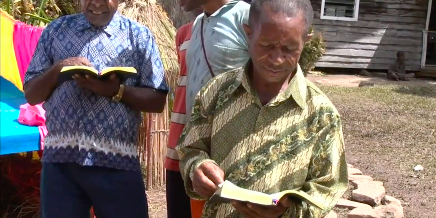 The Kimyal tribe from West Papua, Indonesia, holding a copy of the first New Testament in their language, as depicted in Imagine Life without the Bible. Screengrab from Imagine Life without the Bible.