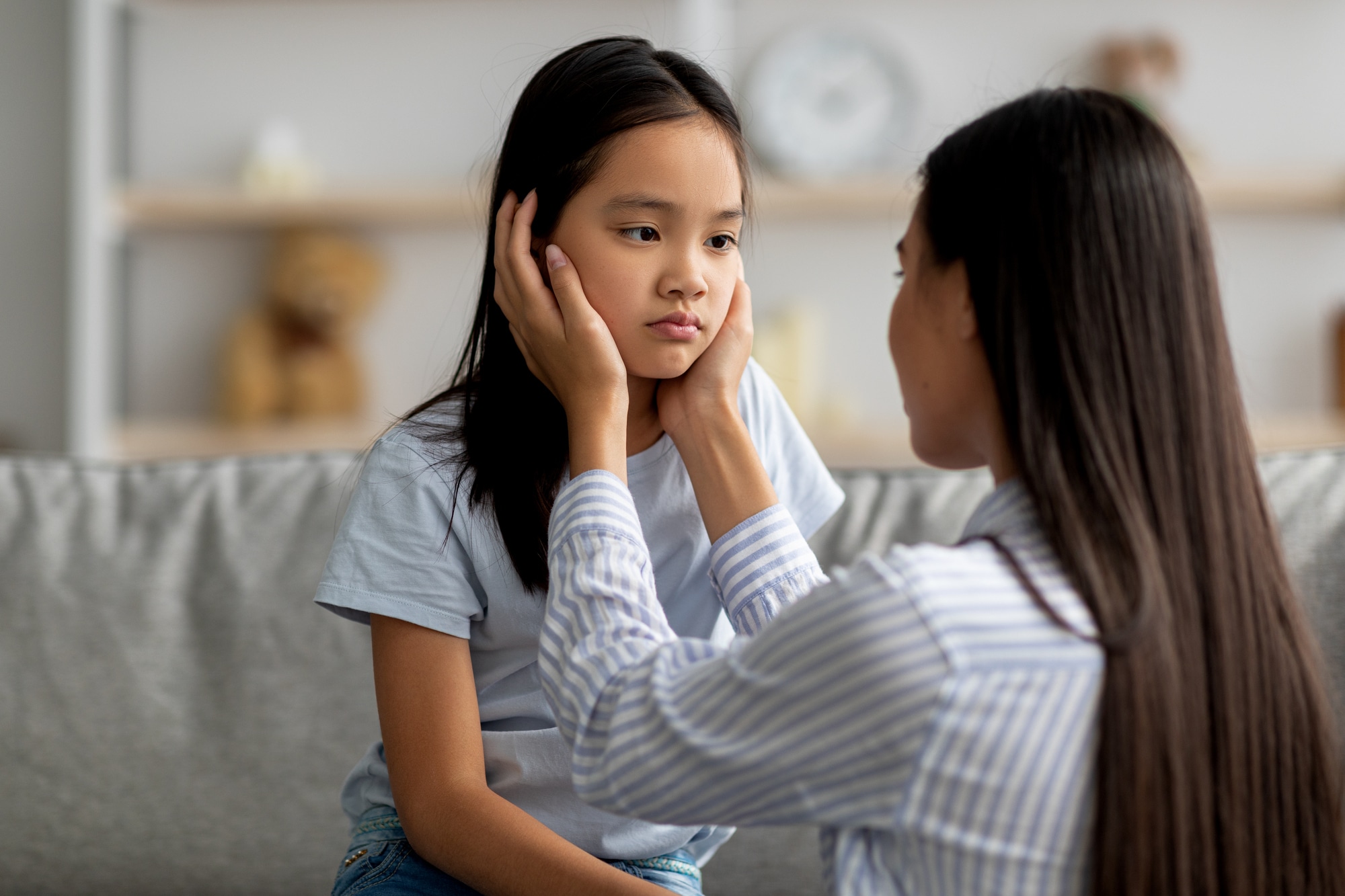 Childhood problems concept. Young mother comforting her sad offended daughter after quarrel at home