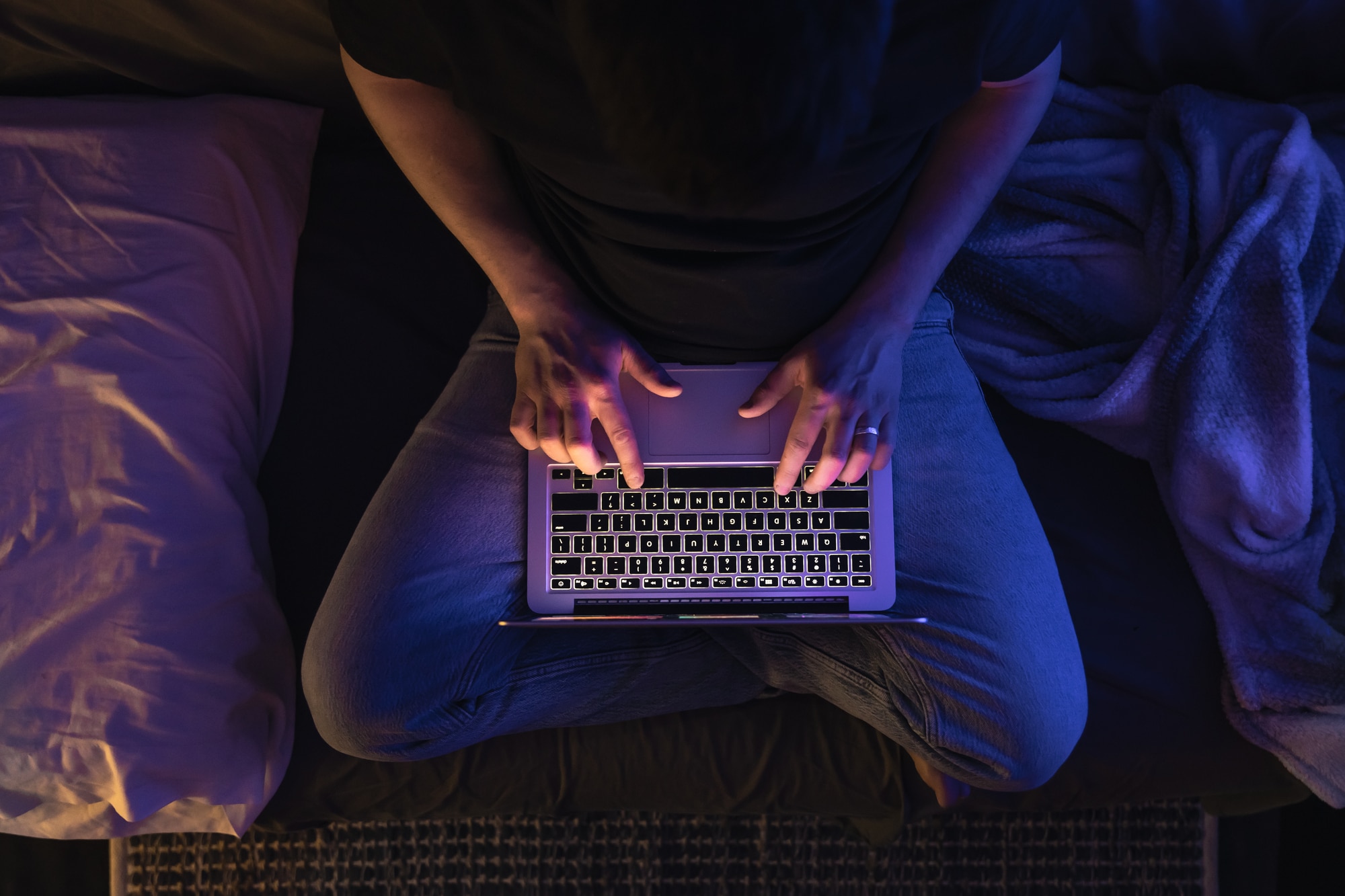 Busy man networking on laptop late at night, typing text, working overtime.