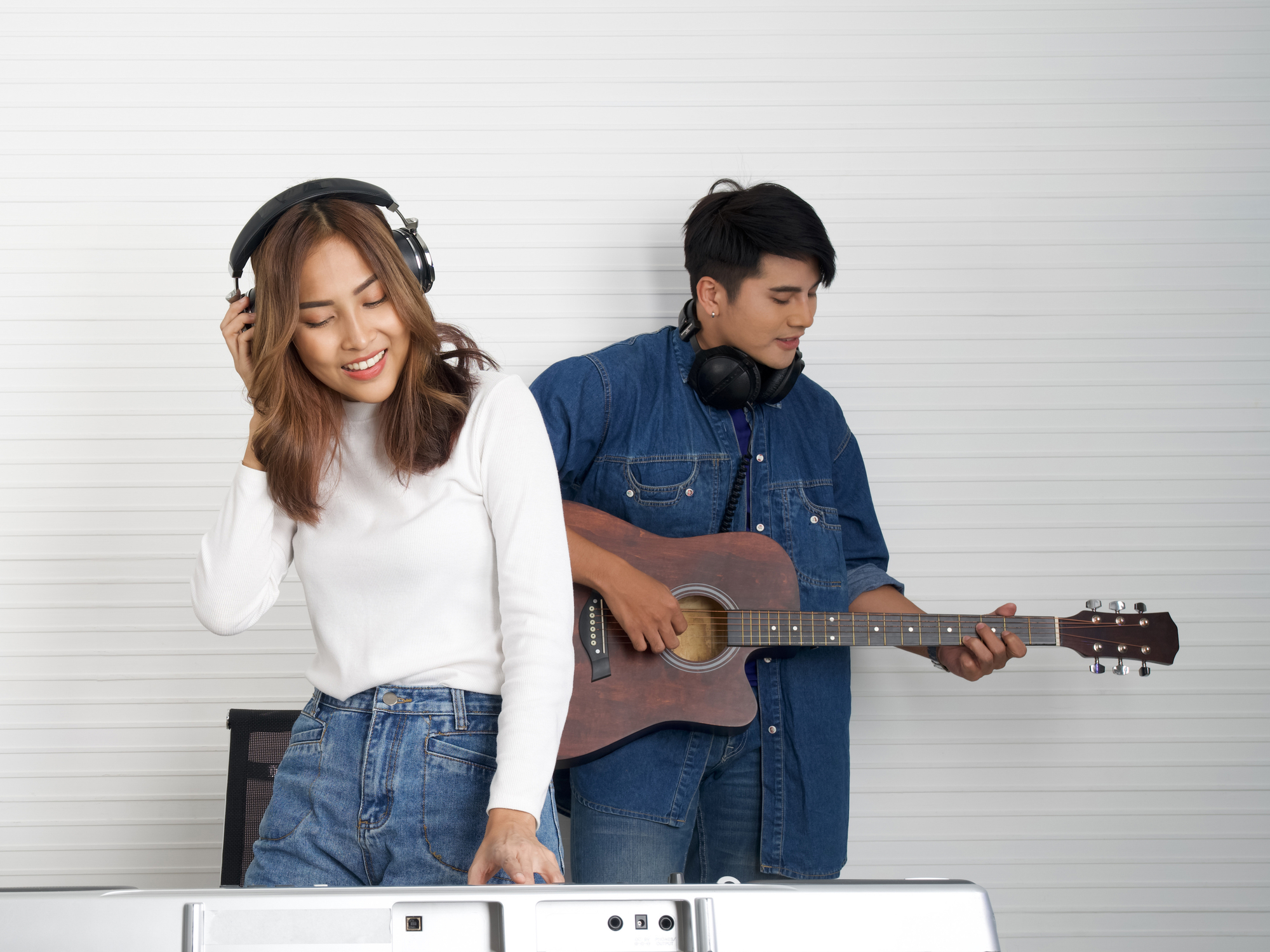 Young asian woman sing while playing an electric keyboard in fro